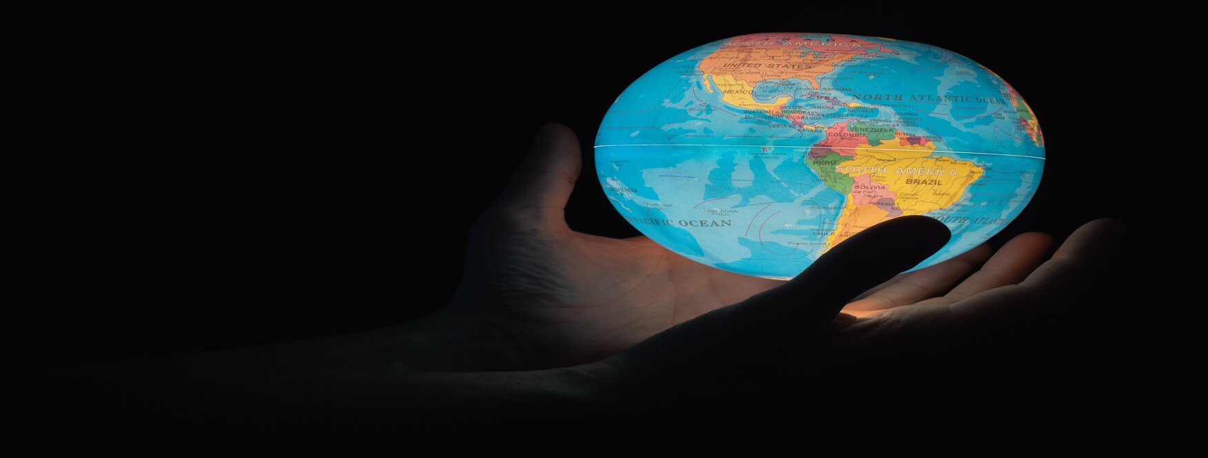 Black background with a hand holding a blue Earth globe